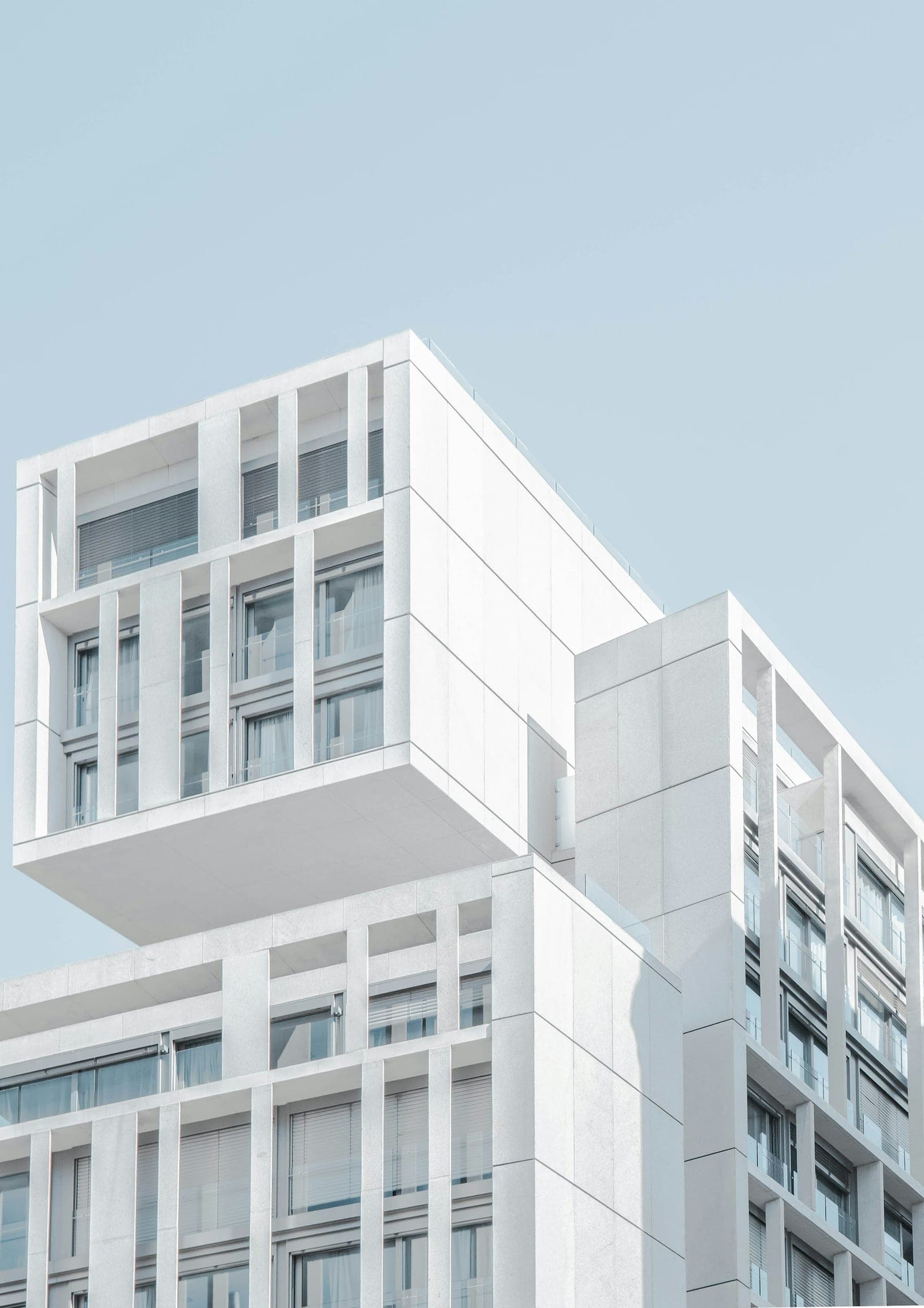 Crisp white modular apartment facade with deep-set windows under a clear sky
